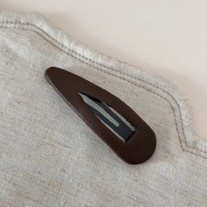 Détail de la pince à cheveux goutte d'eau marron foncé avec texture élégante en cuir