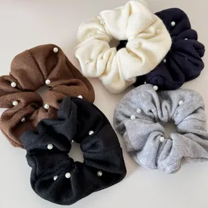 Detailed macro view of knitted fabric scrunchies with white pearl beads in five assorted colors