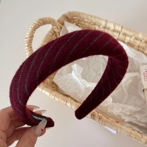 Close-up of burgundy knit headband with handmade label and high-quality wool texture