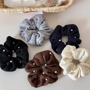 Detailed flat lay of five knitted hair scrunchies with pearls in autumn neutral colors