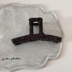 Détail d'une pince à cheveux motif léopard café posée sur un support en lin beige