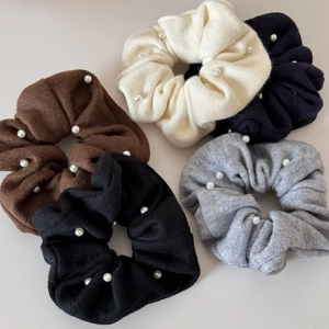 Close-up of five knitted scrunchies with white pearls in beige, blue, brown, grey and black