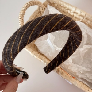 Close-up of thick knitted headband featuring yellow twill stripes and warm wool texture