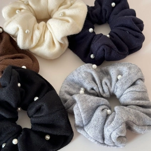 Flat lay of knit scrunchies with faux pearls in assorted neutral colors for winter