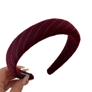Thick burgundy knitted headband with grey diagonal stripes and handmade label