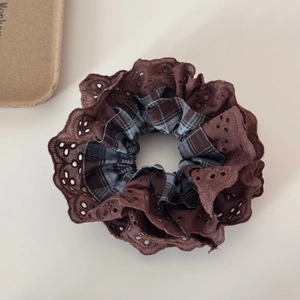 Detail view of deep brown scrunchie with blue plaid fabric and lace embroidery trim