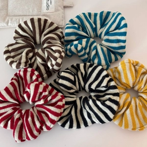 Close-up of five striped knitted oversized hair scrunchies in various vibrant colors