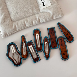 Detailed set of 8 tortoiseshell resin hair clips with blue edges on white background