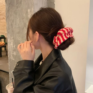 Detail of a red and white striped knit scrunchie on a ponytail for a stylish look