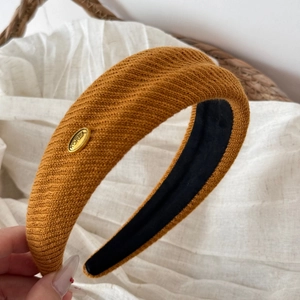 Detail view of the ribbed knit fabric texture and gold logo on the wide headband