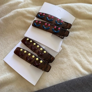 Brown resin duckbill hair clips with cute smiley faces and dots on white card display