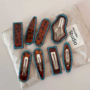 Set of 8 leopard print hair clips with blue edges on a linen bag