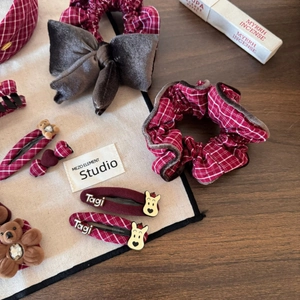 Red plaid hair accessories set with cartoon bear clips and velvet bows on wooden desk