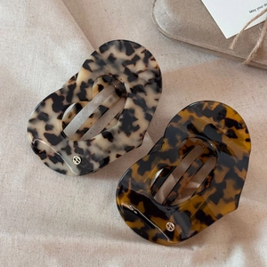 Détail des pinces à cheveux creuses en acétate avec motif écaille et logo métallique fin