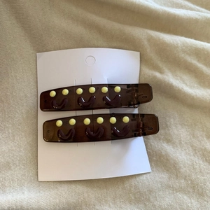 Close-up of brown rectangular hair clips with yellow smiley faces on cream fabric