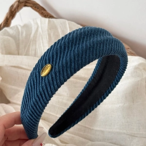 Detail of navy blue ribbed knit headband with gold KOREA metal emblem and anti-slip lining