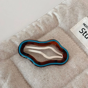 Close-up of irregular wave hair clip with brown leopard print and bright blue edging