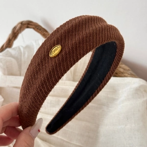 Close-up of brown knitted thick headband with Korea gold metal label and soft fabric texture