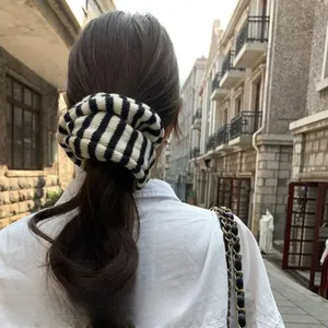 Close-up of oversized black and white striped knit scrunchie with soft ribbed texture
