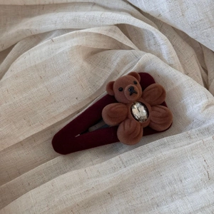 Detail of a vintage red velvet hair clip with a cute brown plush bear and sparkling crystal