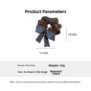 Detail view of brown knit scrunchie with grey polka dot bow measuring 18cm by 13cm