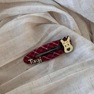 Detail of red checkered fabric BB hair clip with cartoon bear and Tagi letter decor