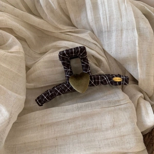 Detail of brown plaid hair claw clip with a green flocked heart and gold metal tag