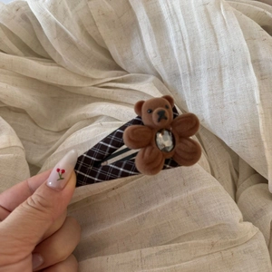 Detail of brown plaid hair clip featuring a flocked teddy bear with a crystal embellishment