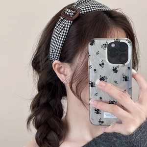 Détail du serre-tête à carreaux avec boucle marron et texture de tissu sur les cheveux