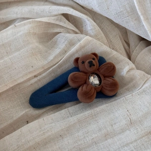 Detailed close-up of navy blue BB hair clip with flocked bear, flower, and crystal accent