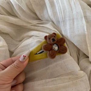 Detailed close-up of a yellow flocked hair clip featuring a cute brown bear with a rhinestone