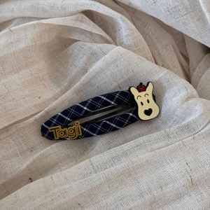 Macro shot of navy plaid fabric hair claw with cartoon bear and Tagi branding