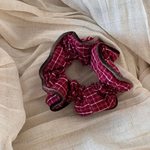 Detailed macro view of burgundy plaid scrunchie with dark brown velvet edge piping