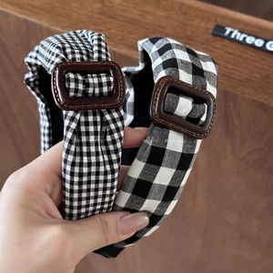 Gros plan de serre-têtes à damier noir et blanc avec des boucles vintage marron