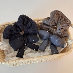 Polka dot and knit bow scrunchies in black and brown set on a woven basket surface