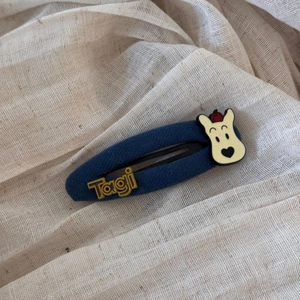 Detailed shot of navy plaid BB hair clip with cartoon dog and Tagi letters detail