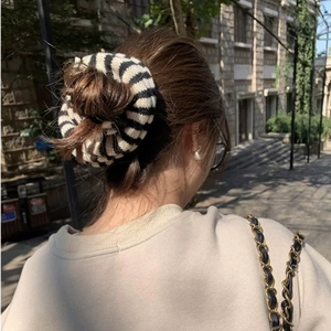 Detail of knitted oversized scrunchie with black and white stripes on a high ponytail