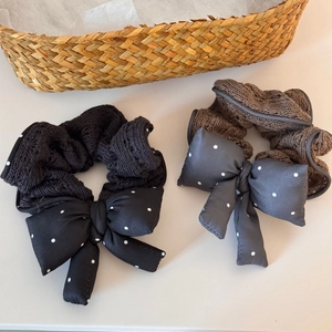 Close-up of knit polka dot bow scrunchies in black and brown colors on beige surface