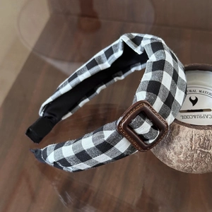 Détail du bandeau rétro à carreaux noirs et blancs avec une boucle carrée marron élégante