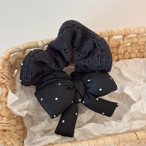 Close-up of black lace and polka dot bow scrunchie on rustic white paper background