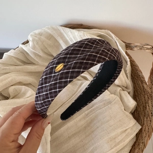 Close-up of brown plaid wide headband with golden Make A Wish logo and velvet lining