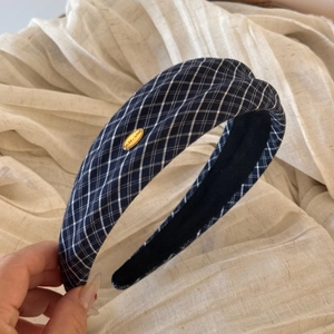 Close-up of navy plaid fabric headband with a gold Make A Wish metal plaque detail