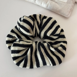 Close-up of black and white striped knitted oversized scrunchie showing fabric texture