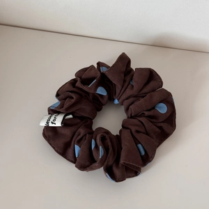 Gros plan d'un chouchou marron à pois bleu clair avec une étiquette en tissu blanc