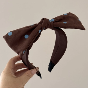 Détail d'un chouchou en tissu marron à pois bleus avec un grand nœud élégant