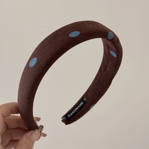Détail d'un chouchou marron à pois montrant l'étiquette fait main et la texture du tissu