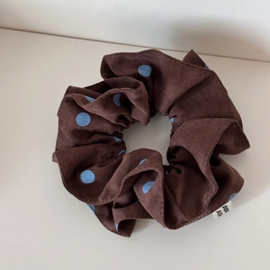 Vue détaillée du chouchou marron à pois bleus avec étiquette en tissu blanc