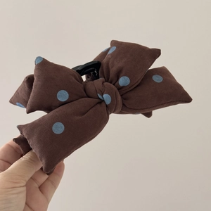 Gros plan sur la pince à cheveux noeud en tissu marron à pois bleus et plastique