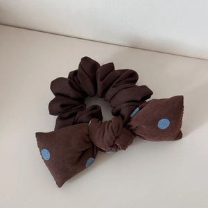 Vue détaillée du chouchou en tissu marron double couche avec un nœud à pois bleu clair