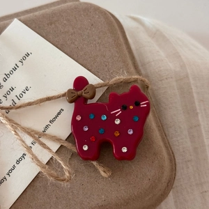 Détail d'une pince à cheveux chat rouge foncé avec strass colorés et nœud décoratif